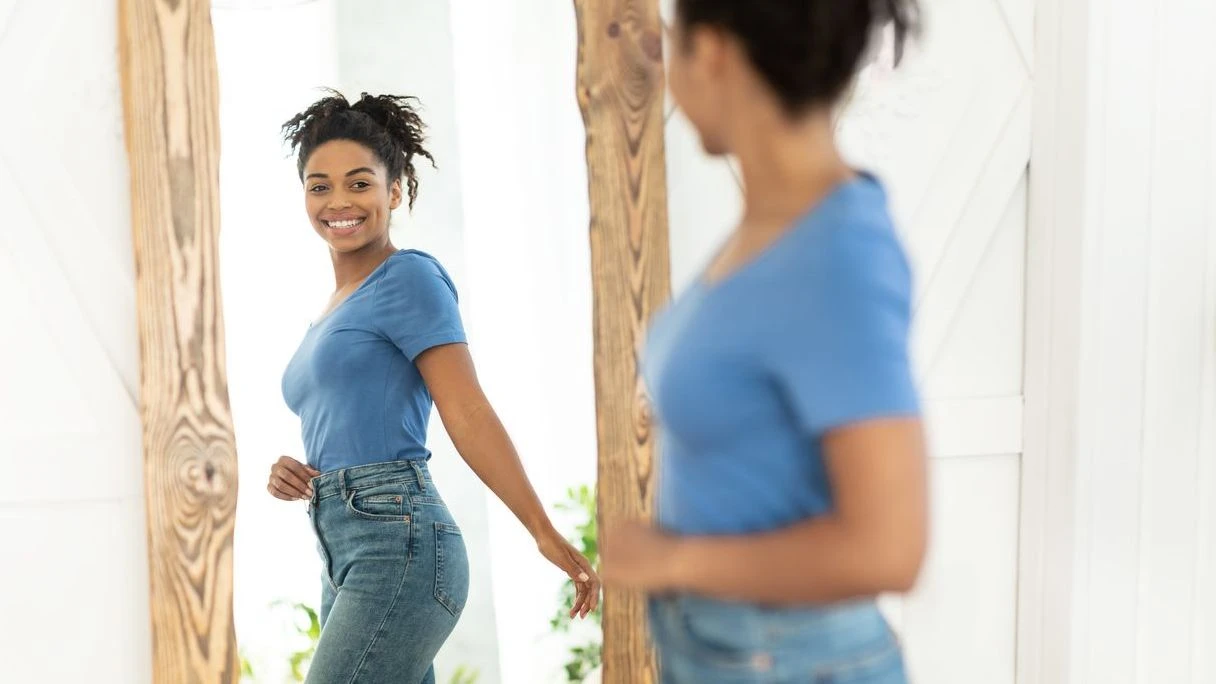 Joyful African American Girl After Slimming Looking In Mirror Indoor stock photo