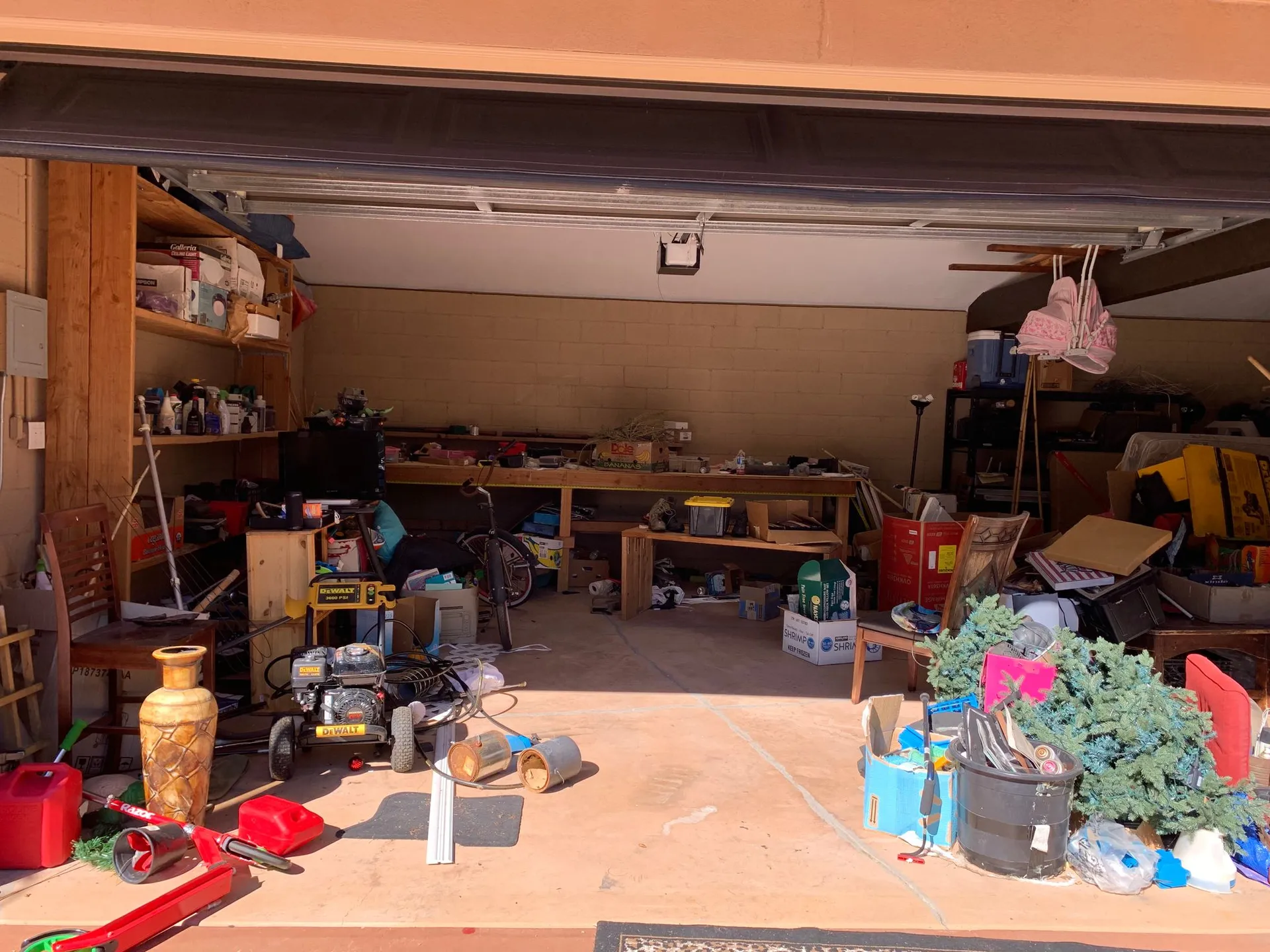 A cluttered garage filled with scattered tools, boxes, household items, and miscellaneous objects, creating a disorganized space.