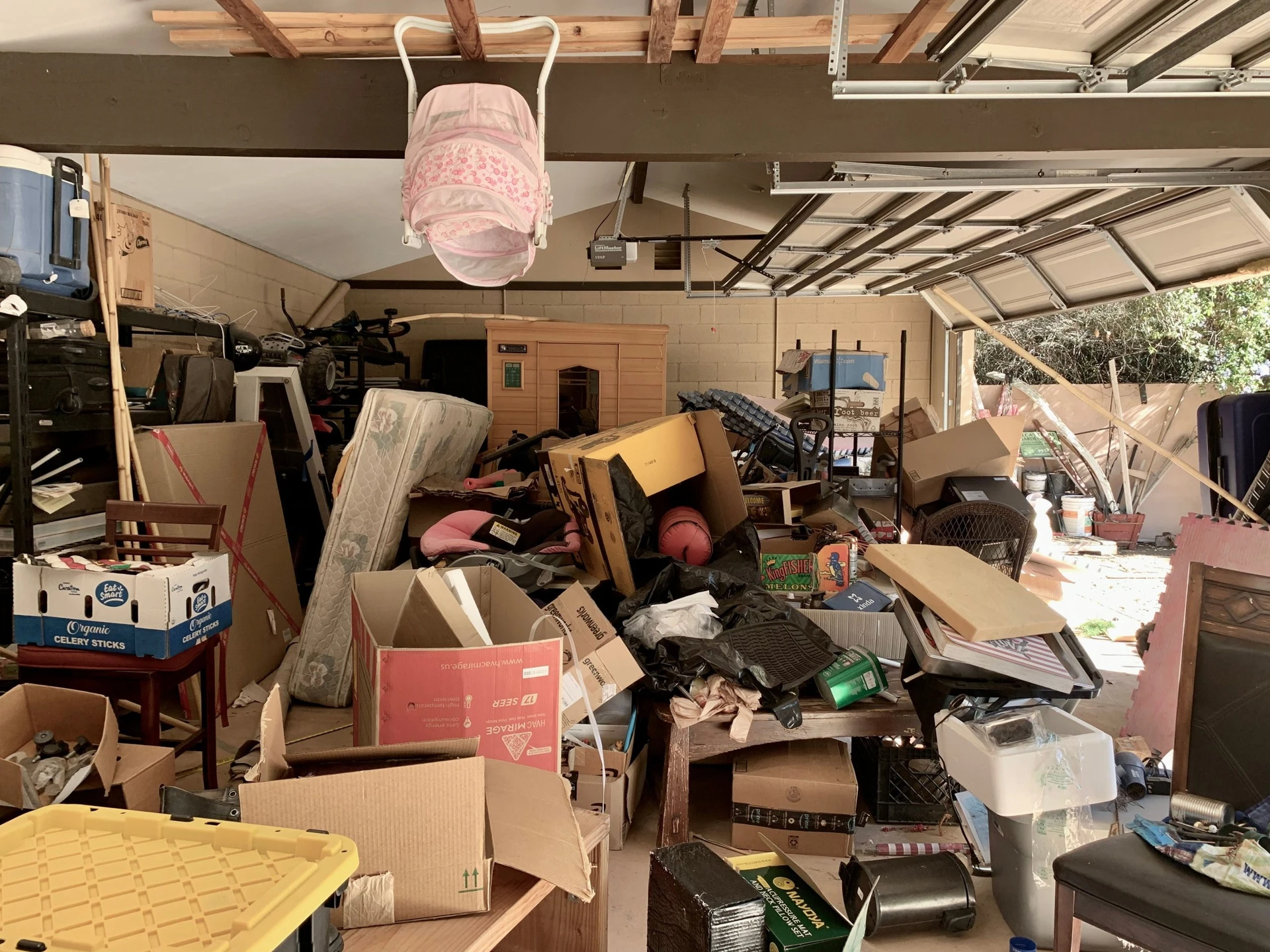 A garage completely filled with clutter, including boxes, furniture, and miscellaneous household items, creating an overwhelming mess.