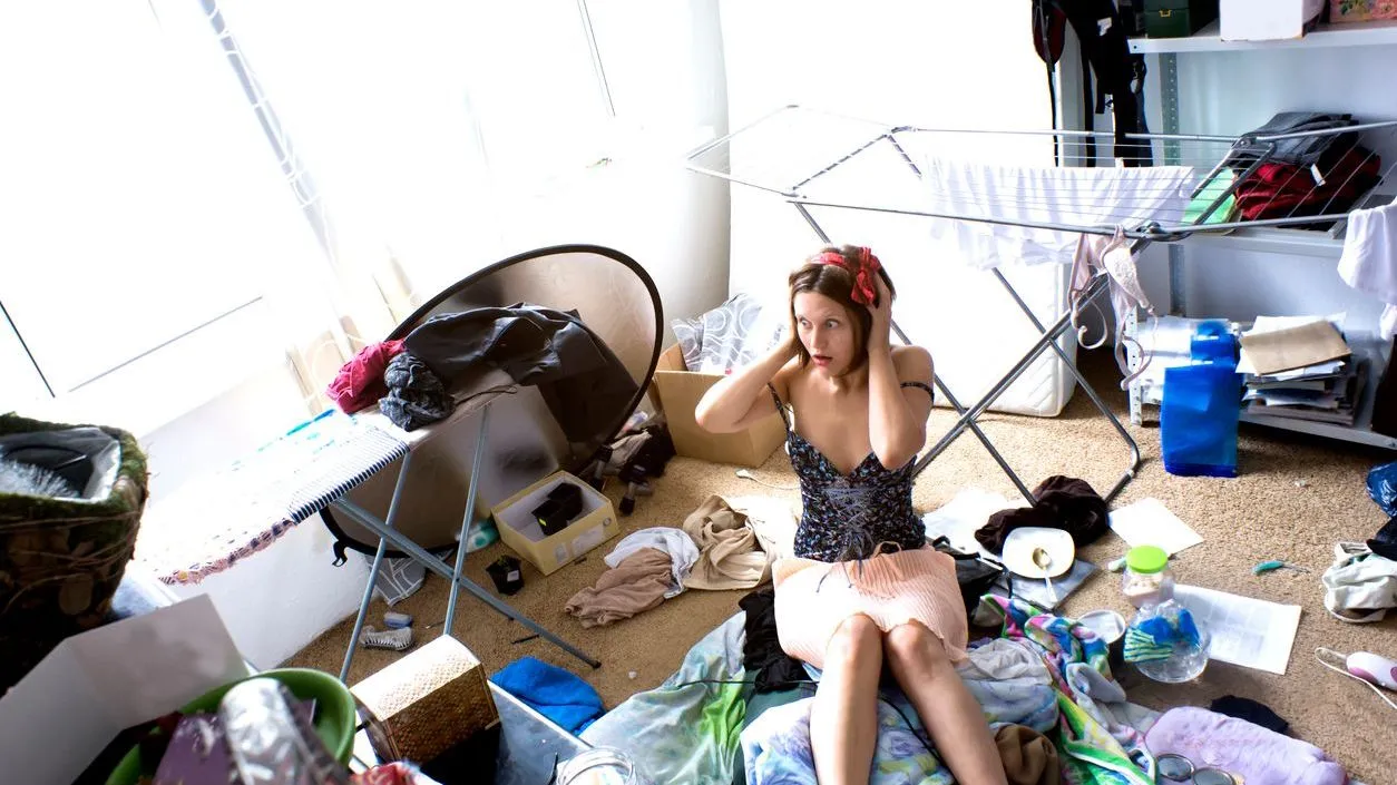 Beautiful woman is expressing panic in her really messy room stock photo
