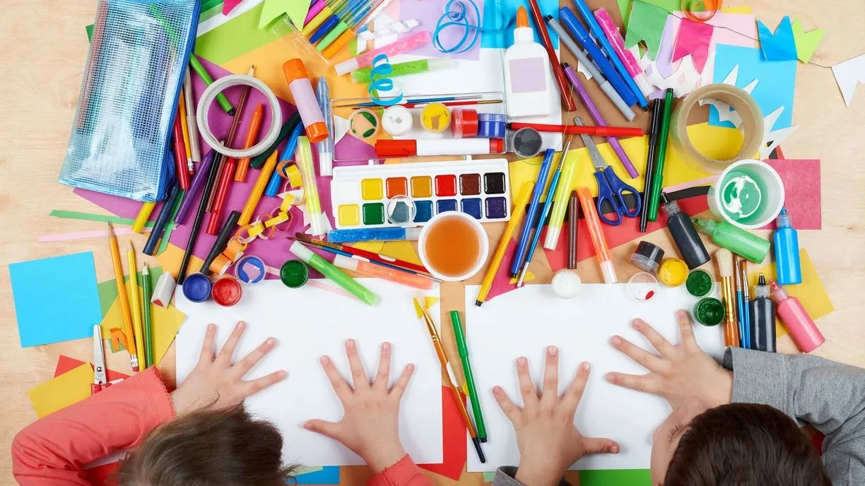 Child drawing top view. Artwork workplace with creative accessories. Flat lay art tools for painting.