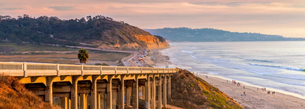 A scenic view of the Del Mar coastline during sunset, featuring the iconic bridge, golden cliffs, and serene ocean waves, symbolizing Organizing Services in Del Mar.