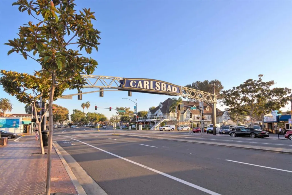 Carlsbad sign at a picturesque street intersection surrounded by shops and trees, representing the vibrant community in Carlsbad, CA.