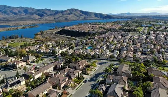 Aerial view of a picturesque Chula Vista neighborhood with scenic mountains and a peaceful lake in the background.